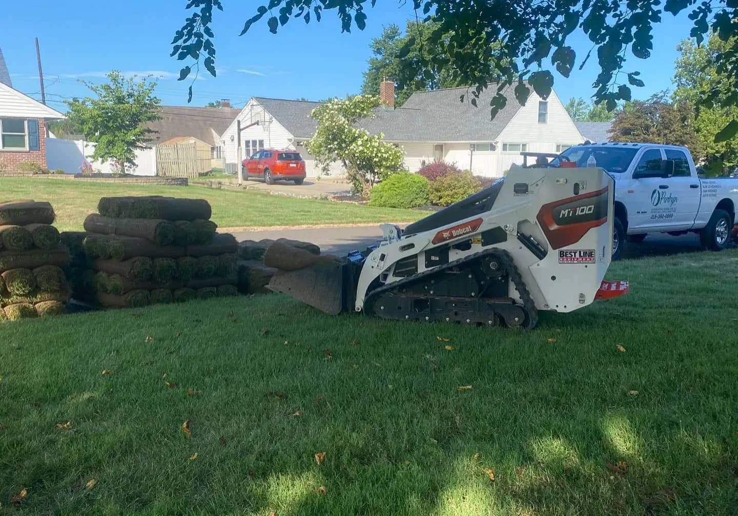 Sod installation process with equipment placing fresh grass rolls on a residential lawn